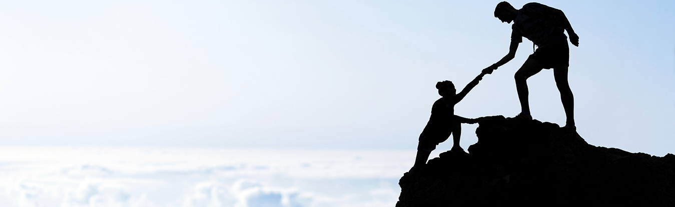 A man helping another climber to the peak.