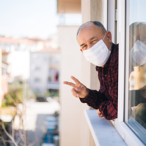 Man wearing surgical mask leaning out his window