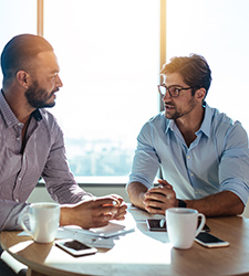 Two male attorneys talking at a table.